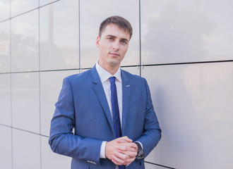 Portrait of a young businessman standing over blurred background outdoors