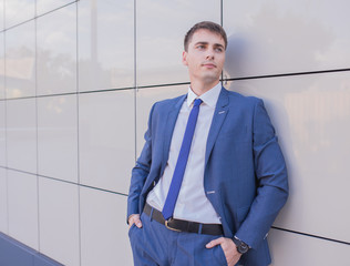 Portrait of a young businessman standing over blurred background outdoors