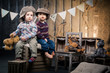 Two little boys in caps sitting on boxes in the studio around so