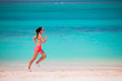 © travnikovstudio - Fit young woman running along tropical beach in her sportswear
