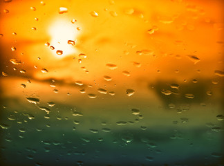 Wall Mural - Water drops on a window glass after the rain. The sky with clouds and sun on background