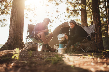 Wall Mural - Couple cooking food outdoors on a camping trip