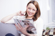 © Sebastian Gauert - Pretty young brown haired girl sitting smiling on couch enjoying reading a fashion magazine