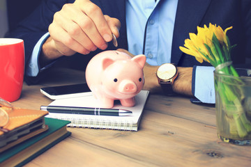 man and piggy bank on wooden table