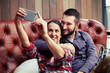 couple sitting on sofa and taking a selfie picture