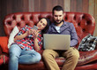 © ArtFamily - couple sitting on sofa and using gadgets