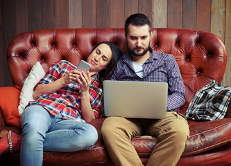 Wall Mural - couple sitting on sofa and using gadgets