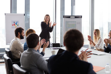 Business people clapping hands during the meeting in modern office.