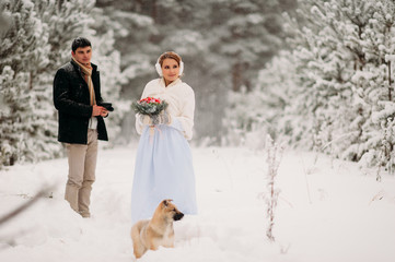 couple with a dog in winter forest