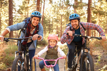 Wall Mural - Gay Male Couple With Daughter Cycling Through Fall Woodland