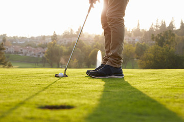 Close Up Of Male Golfer Lining Up Putt On Green