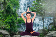 © napatcha - young woman practicing yoga on the cascade and forest
