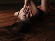 © maksimvostrikov - Seductive, sensual and passionate young charming lady in underwear with dark beautiful long hair, closed eyes and sexy figure is lying stretched on the wooden floor and teasing us, finger near lips