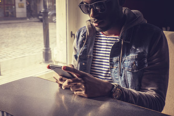 Wall Mural - Blackman in sunglasses using smartphone.