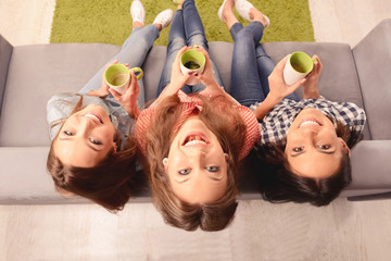 Wall Mural - Top view photo of cheerful girls sitting on couch with cups