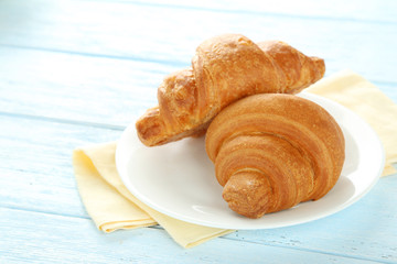 Wall Mural - Tasty croissants on plate on blue wooden background