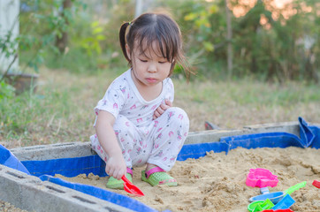 Wall Mural - Little asian girl playing in sandbox