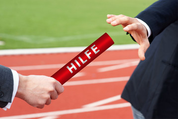 Hilfe geben oder annehmen - Staffelstab Weitergabe im Stadion - Closeup 