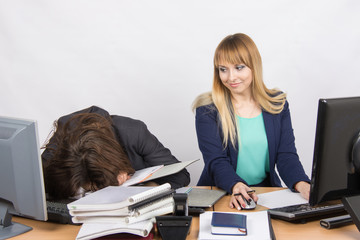 Female colleagues in the office, one had fallen asleep on a pile of folders, and the second looked at her