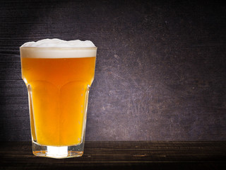 Wall Mural - Glass of beer against dark wooden background, with copyspace