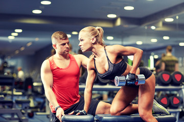 young couple with dumbbell flexing muscles in gym