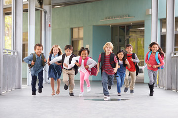 group of elementary school kids running in a school corridor