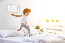 Happy Child Girl Jumps And Plays Bed