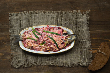  salad herring under a fur coat on a wooden table in the backgro