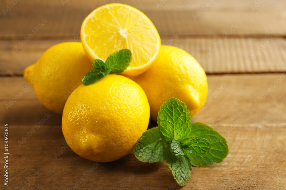 Sliced fresh lemons with green leaves on wooden background