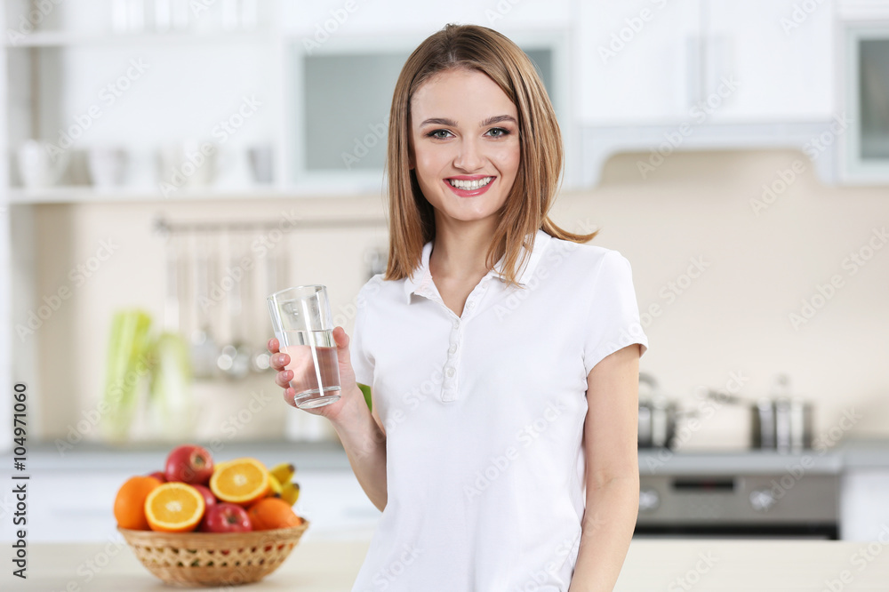 Young woman drinking water from glass in the kitchen