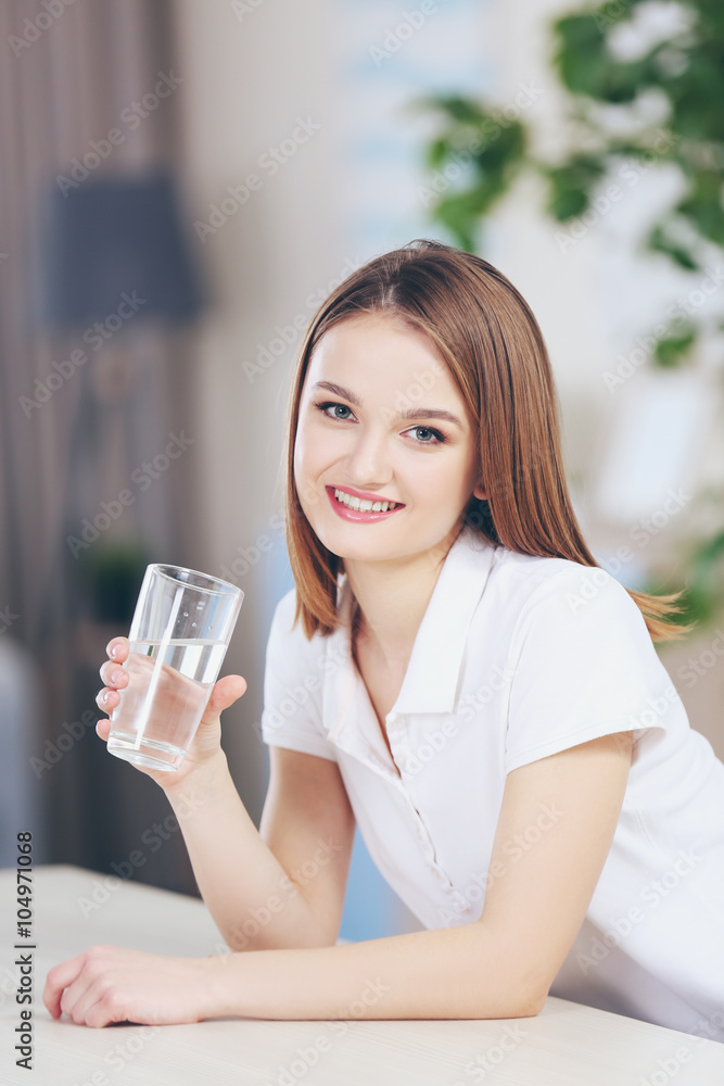 Young woman drinking water from glass in the kitchen