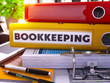 Yellow Ring Binder with Inscription Bookkeeping on Background of Working Table with Office Supplies and Laptop. Bookkeeping Business Concept on Blurred Background. 3D Render.