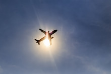 Silhouette Airplane Taking Off Over Blue Sky At Sun Background