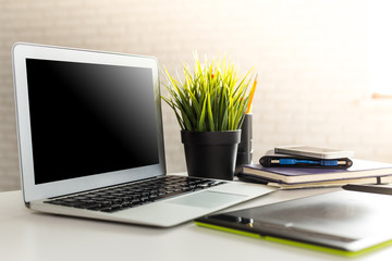 Laptop with blank screen on table in office room