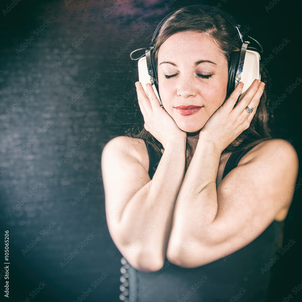 Pretty Girl With Retro Headphones Listening. A pretty woman listening to  large, retro headphones and smiling in a studio. Classic, authentic film  look. Stock Photo | Adobe Stock, image size:1000x1000