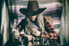 Cowgirl Gunslinger Poker Cards. Old West Cowgirl Gunslinger Sitting At Table Player Poker With Peacemaker Gun, Edited In Vintage Film Style.