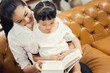© torwaiphoto - Mom teaching daughter to read at home