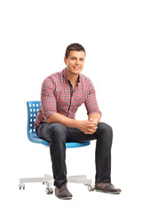 Poster - Young cheerful man sitting on a chair