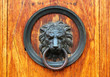 Fragment of old wooden door with bronze lion's head as a doorknocker