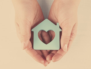 Poster - Female hands with model of house on wooden table background