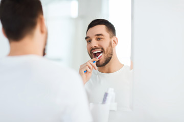 Canvas Print - man with toothbrush cleaning teeth at bathroom