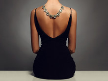 Beautiful Back Of Young Woman In A Black Sexy Dress.Girl With A Necklace