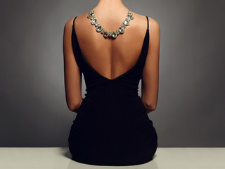 Wall Mural - beautiful back of young woman in a black sexy dress.girl with a necklace