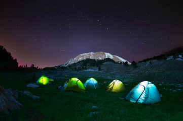 illuminated yellow camping tent under stars at night