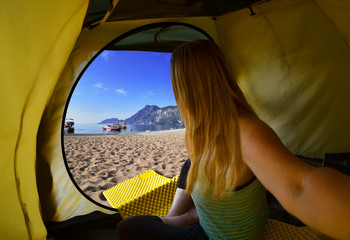 Happy woman sitting in a tent ,view of mountains ,sky and sea in Turkey