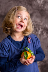 Wall Mural - little funny girl with mandarin orange