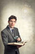 © Stillkost - Young businessman looking at a book with magnifying glass