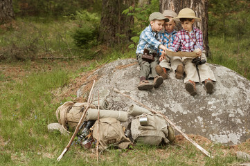 Boys travelers sitting on a large rock with a map