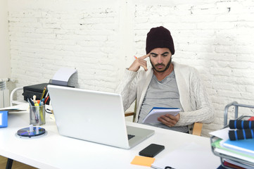 Wall Mural - trendy businessman in cool hipster beanie writing on pad working in at modern home office with computer