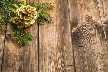 Wall Mural - Wooden background with christmas decoration, golden pine cones hanging on branch of christmas tree